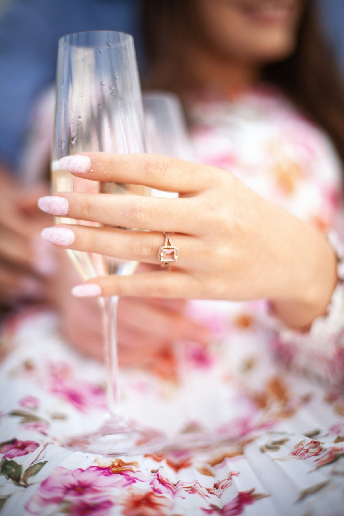 Woman with a diamond ring holding a glass of champagne