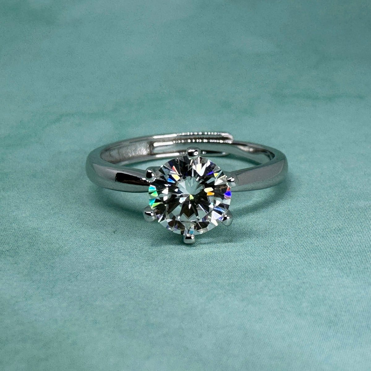 Diamond engagement ring on a teal background