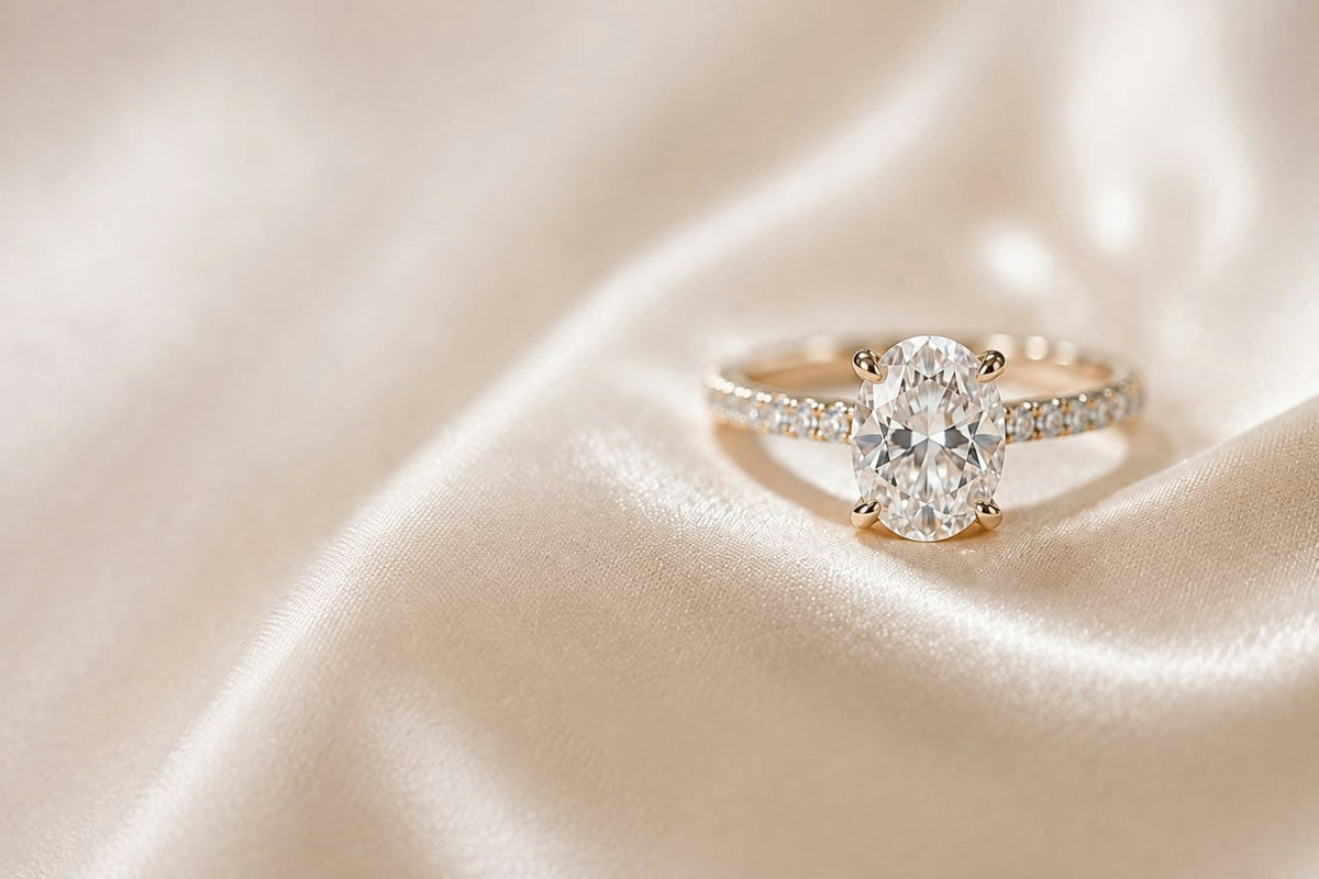 Oval diamond engagement ring with a gold band on champagne silk